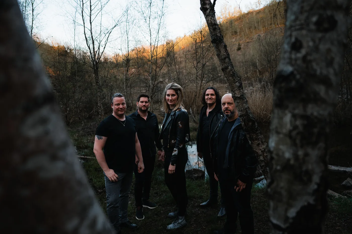 The five members of Go By Brooks in a woodland clearing